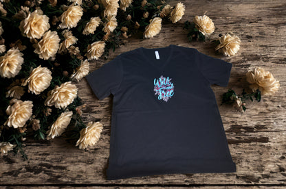 Black t-shirt with colorful graphic design  on a wooden surface with flowers
