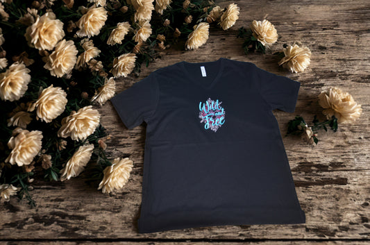Black t-shirt with colorful graphic design  on a wooden surface with flowers